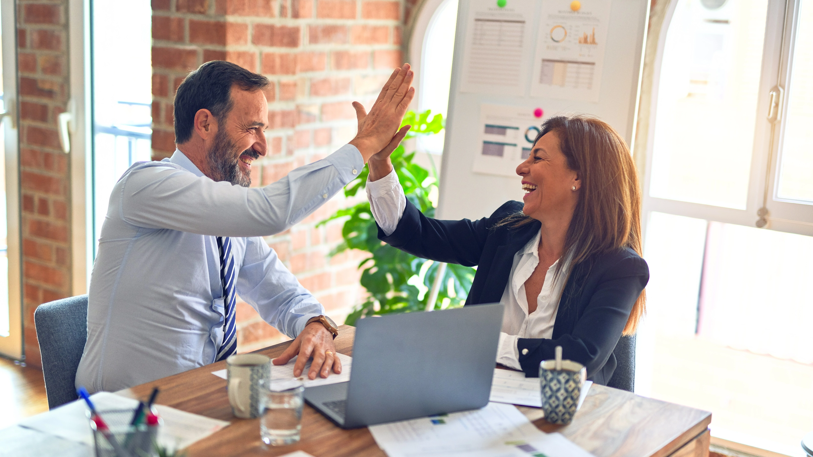 2 Menschen am Schreibtisch geben sich high five