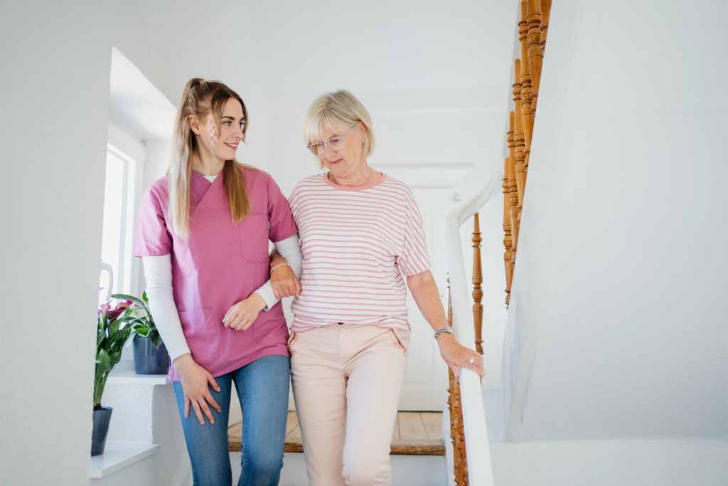 Pflegerin mit älterer Frau auf einer Treppe