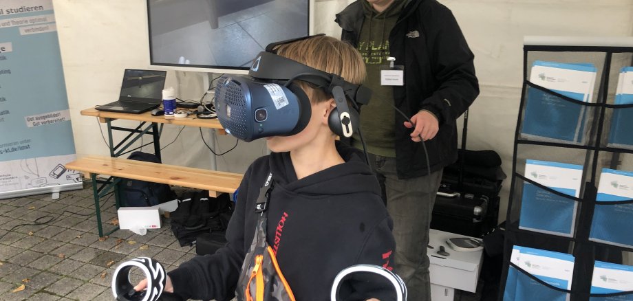 Ein Junge trägt eine VR Brille und hat zwei Controller in den Händen